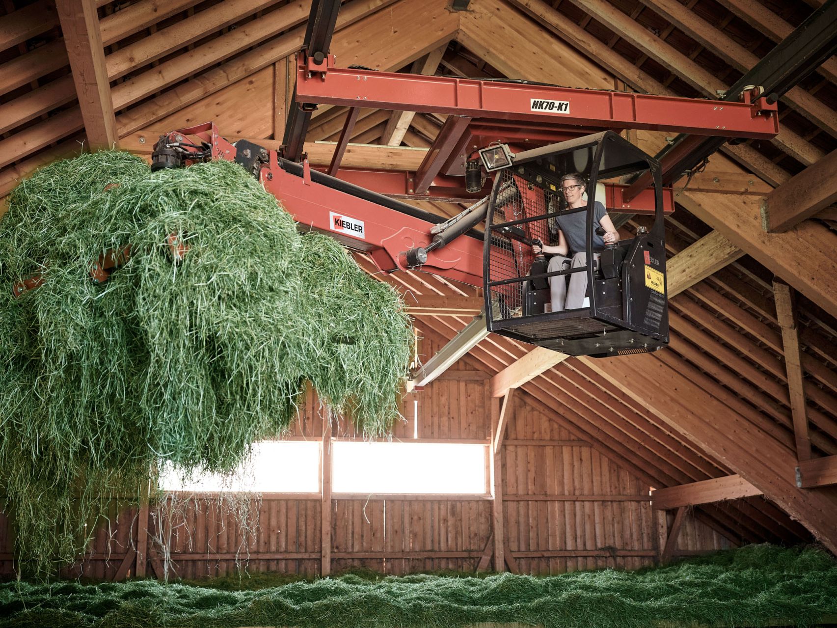 Eine Landwirtin sitz in ihrem Heukran und bereitet Heu auf.